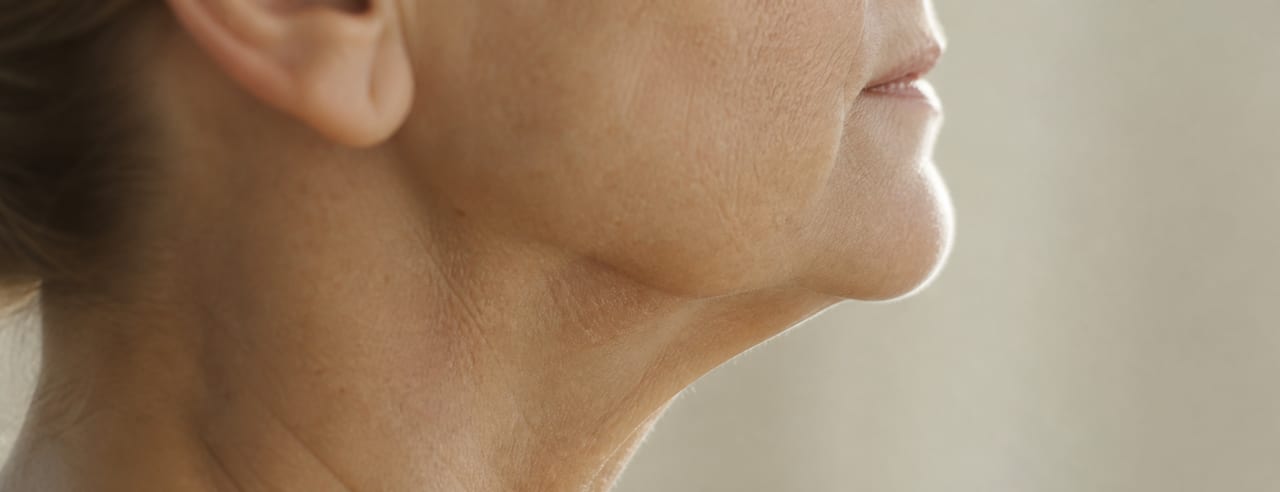 Profil strict d'une femme d'une soixantaine d'années : ovale, angle mandibulaire et haut du cou soulignés par un contre-jour très doux.